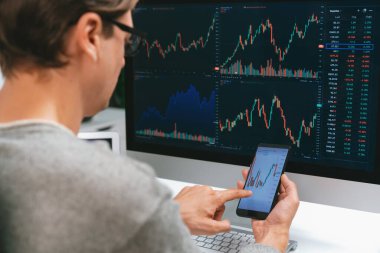 Akıllı borsa yatırımcıları ekranda akıllı telefon ile piyasa borsasını işaret ederek dizüstü bilgisayarın yanı sıra en yüksek dinamik yatırım oranını göstererek, modern işyerindeki veri planlamasına odaklanıyorlar. Bireysel.
