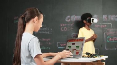 Beyaz bir kız kameraya el sallamak için dizüstü bilgisayar kullanırken Afrikalı çocuk VR takıyor. Yetişkin bir kadın kameraya selam verirken kod ve komut ile tahtada duruyor. Öğretim