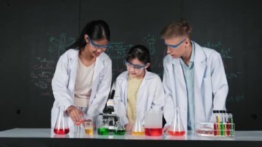 Zeki kız deney yapmak için heyecanlanan çeşitli öğrenciler iken beher kabına renkli solüsyon döker. Profesyonel bilim adamı kimyasal teoriyle kara tahtada deney yapmaya hazırlanıyor. Öğretim