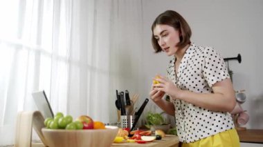 Kafkasyalı anne, modern mutfakta dizüstü bilgisayarda yemek tarifine bakarken salata yapmak için yemek hazırlıyor. Yetenekli ev bekçisi taze sebze kullanarak kahvaltı hazırlıyor. Pedagoji.