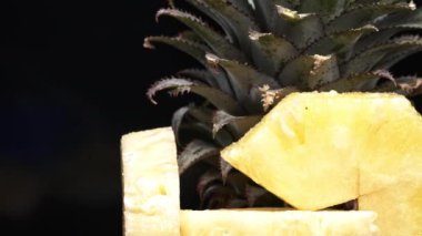 Bir dilim ananaslı siyah bir fon. Güneş tarafından öpülen altın et ve ışıltı, kabuğun yanında beyaz bir ipucuyla tezat. Siyah arkaplanlı ananasın sarı eti. Geliştirilebilir.