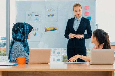 Çok kültürlü çalışma grubu. Farklı etnik kökenden iş kadınları, Kafkasyalı, Asyalı ve Araplardan oluşan bir ekip ofiste dizüstü bilgisayarla birlikte çalışıyor. Çok ırklı takım çalışması konsepti. uds