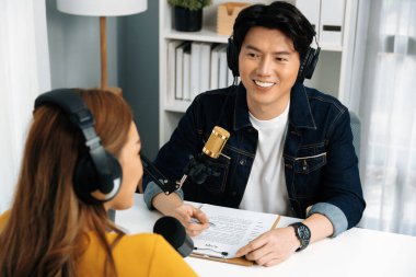 Gülümseyen radyo etkili sunucusu kulaklık takıyor kadın konuşmacı ile röportaj yapıyor sosyal medya internet sitesinden dinleyicilere bilgi paylaşıyor stüdyo kaydında sabah canlı yayın kanalı. İnfobahn.