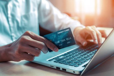 Genç adam, laptop bilgisayar başvurusu ya da web sitesinde online alışveriş yapmak için kredi kartı kullanıyor. E-ticaret ve online alışveriş konsepti. uds