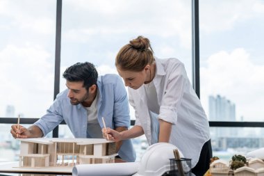 Akıllı beyaz mimar mühendis takımı ev modelini ölçmek için birlikte çalışıyor. Bir grup profesyonel iç mimar tasarım inşaatı hakkında fikir paylaşımı ve beyin fırtınası yapıyor. İzleme.