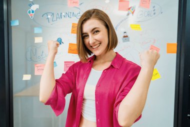 Beyaz tahtanın önündeki kameraya zihin haritası ve renkli yapışkan notlarla bakarken gülümseyen ve kendinden emin bir şekilde poz veren genç beyaz iş kadınının portresi. - Yakın çekim. Tertemiz..