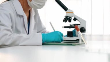 Laboratuvar kimya araştırmacısı mikroskop kullanarak yeni ilaç ya da tedavi geliştirir. Laboratuvar mikrobiyoloji ekipmanları ile bilimsel uzmanlık ile sağlık hizmetlerinin teknolojik gelişimi. Ağır çekim. Katı.