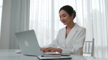 Çalışma masasında internet içeriği için dizüstü bilgisayar kullanan genç bir iş kadını ya da evden çalışan bir sekreter. Canlılık