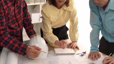 Mimari döküman, ölçüm araçları ve ahşap blokların modern ofiste etrafa saçıldığı masa üzerine planlar yapma konusunda akıllı mimar ve güvenlik mühendisi tartışması. - Yakın çekim. Tanımlama.
