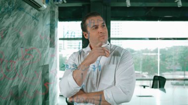 Akıllı iş adamı cam tahtanın önünde bir proje başlatmayı düşünüyor. Gülümseyen erkek proje yöneticisi yaratıcılık pazarlama stratejisini gösteren renkli yapışkan notlara bakıyor. Yönlendirici.