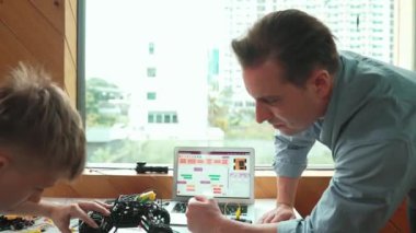 Öğretmen yardımı öğrencisi araba modelini tamir ediyor ve liseli çocuk STEM sınıfında robotu tamir etmek için ekipmanları dinlerken programlama sistemi ya da kodlama komutu veriyor. Arkadan bak. Öğretim