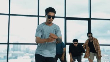 Profesyonel hipster, çeşitli çok kültürlü arkadaşlarıyla birlikte adım atıp dans ediyor. Gökyüzü dövüşçüsü ve şehir manzaralı pencerenin yanında duruyor. Break dans. Açık hava sporları konsepti 2024 hiphop..