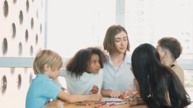 Çizim kitabında işaret kullanarak çeşitli öğrencilerin ve zeki öğretmen çizimleri ve boyamaları mutlu olsun. Çok kültürlü, zeki bir öğrenci yetenekli beyaz bir eğitmenle konuşurken çizim kitabı kullanıyor. Etkinlik.