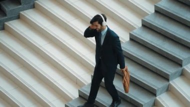 Merdivenlerden inerken kulaklıktan müzik dinleyen mutlu bir iş adamı. Yönetici, satışların artmasını, başarılı projeleri veya yeni pozisyonları kutlamak için dans ediyor. Sevinçli..