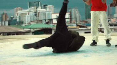 Profesyonel Asyalı sokak dansçısı çatıda çok kültürlü arkadaşlar dans ederken B boy dansı yapıyor. Genç modern dans grubu hip hop hareketi yapıyor. Tarz, moda, aksiyon. Açık hava sporu 2024 hiphop..