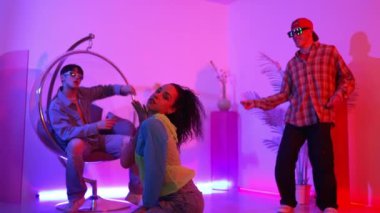 İspanyol hipster renkli kıyafetler giyer ve serbest stil müziğe el sallar. Profesyonel break dansçı neon ışıklarıyla ve modern stüdyo arkadaşlarıyla coşkuyla dans ediyor. Mutluluk.