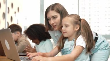 Çok kültürlü bir öğrenci dizüstü bilgisayar kullanarak mühendislik kodları yazarken öğretmen program hakkında açıklama ve öğretim yapıyor. Profesyonel eğitmen BTMM sınıfında programlama sistemini öğrenmeye yardım ediyor. Etkinlik.