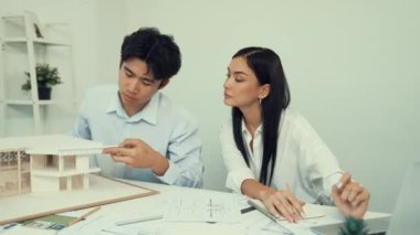 Genç, zeki, yakışıklı mühendis ev modelini ölçerken genç, beyaz, iç tasarımcı önemli noktayı işaret ediyor. Birlikte çalışıyoruz, takım olarak çalışıyoruz. Yaratıcı tasarım konsepti. Tertemiz..