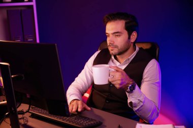 Gülümseyen zeki işadamı, elinde kahve fincanı olan satış ekibiyle buluşuyor ve geceleri Mor Neon Light Home Office 'deki bilgisayar ekranında ürün hedef pazarını araştırıyor. Tahmin et..