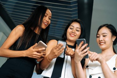Üç kadın arkadaş ellerinde cep telefonuyla sohbet ediyorlar. Sosyal medya, dedikodu haberleri ve online alışveriş kavramı. uds