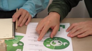 Mükemmel iş adamları, yeşil enerji grafiği kullanımı olan karmaşık bir masada eko ev projesini tartışıyor alternatif enerjiyi seçiyor ya da analiz ediyor, karbonu azaltıp dünyayı kurtarıyor. Eline odaklan. Tanımlama.