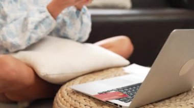 Genç bir kadın internet bankacılığı için kredi kartıyla dizüstü bilgisayar kullanıyor. Evinde online ödeme kapısı ile E ticareti yapıyor. Banka kartıyla modern ve kullanışlı online satın alma. Blithe