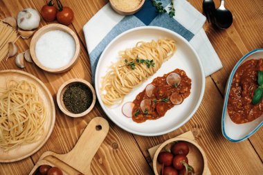 Lezzetli yiyecekler, ev yapımı spagetti, kıymalı domates sosu ve fesleğen fırlatma elementleri, şef masası dekoratif baharatlarla servis ediliyor. Varsayım.