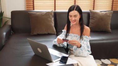 Genç bir kadın internet bankacılığı için kredi kartıyla dizüstü bilgisayar kullanıyor. Evinde online ödeme kapısı ile E ticareti yapıyor. Banka kartıyla modern ve kullanışlı online satın alma. Blithe