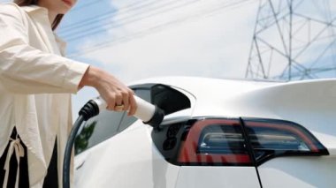 Alttaki görüntüde kadın EV araba aküsünü şarj ediyor elektrik şebekesine bağlanıyor elektrik endüstrisi çevre dostu araç için elektrik endüstrisi olarak. Yararlı