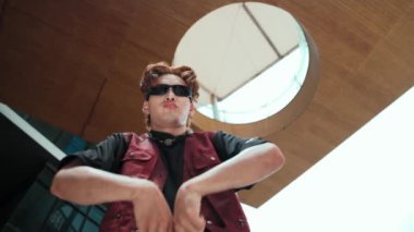 Kameraya poz veren modern dansçı ve düşük açılı kamera. Hip hop tarzında dans eden genç hip hop dansçısının portresi. Açık hava sporu 2024. Hareket atışı. Serbest stil. hiphop.