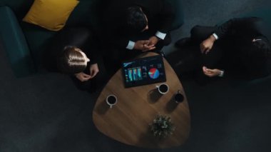 İş adamlarının iş birliği ve tokalaşma konusunda anlaşmalarını yukarıdan aşağıya izledik. Çeşitli gruplar, planlarını açıklarken finansal istatistiklerle birlikte tablet gösteriyor. Müdürlük.