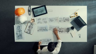 Yetenekli inşaat mühendisinin ev modeline bakarken oturup fikir yazması. Mimarın ya da tasarımcının yaratıcı bina inşaatını planlama ve düşünme havadan görünüşü. Hizalama.