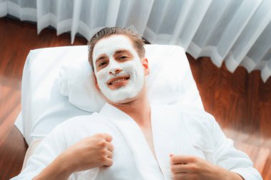 Kaplıca salonunun sakin atmosferi, insan müşterisi modern gün ışığında lüks yüz kremi masajıyla kendini yenileme zevkine kapılıyor. Yüz bakımı ve güzellik konsepti. Sessiz.