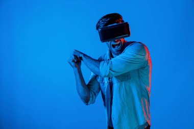 Kafkasyalı bir adam VR cam takıyor ve hareket eden el kol kılıcını tutuyor. Oyuncu, gelecekteki sanal gerçeklik kulaklığını ya da gelecekteki yenilikleri kullanarak meta dünyaya giriyor ya da aksiyon oyunu oynuyor. Sapma.