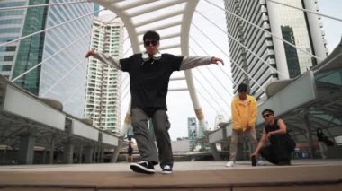 Asyalı hippiler şehir merkezinde alçak açılı kamerayla çevrili insanlar tarafından ayak sesleri çıkarırken profesyonel çok kültürlü dansçılar neşelenin. Break dans konsepti. Açık hava sporu 2024. Yumuşak bir şekilde..