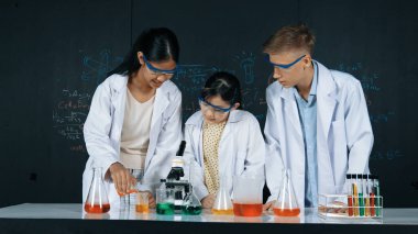 Zeki kız deney yapmak için heyecanlanan çeşitli öğrenciler iken beher kabına renkli solüsyon döker. Profesyonel bilim adamı kimyasal teoriyle kara tahtada deney yapmaya hazırlanıyor. Öğretim.