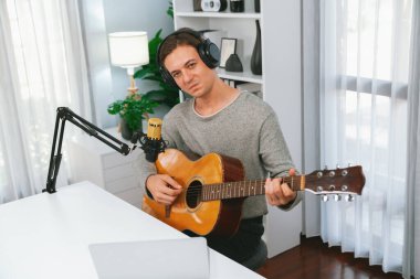Akıllı şarkıcı görünümlü kamerada sunucu kanalı, şarkı söylerken gitar çalmak, sosyal medya kanalında yayın yapmak, modern stüdyo kaydında video kaydedici olarak kulaklık takmak. Bireysel.