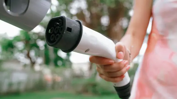 在自然绿色公园的停车场 女服务员正在给电动汽车充电 清洁能源技术用于可持续和生态友好旅行的充电式车辆 同步操作 — 图库照片