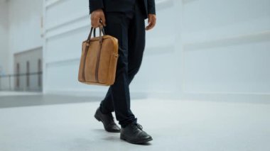 Profesyonel iş adamının bacağını tutarken yakın plan fotoğrafı. Proje yöneticisinin bacağa odaklanmış görüntüsü. Seyahat, taşınma, yolculuk, yürüyüş, yeni bir pozisyon alma, iş değiştirme. Sevinçli..