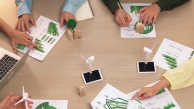 Eko evi projesini yel değirmeni tasarım modeli ve karbon ayak izini azaltmak için yeşil enerji kullanım grafiği ile toplantı masasında tartışan harika bir iş ekibi. Dünyayı kurtarın. Eline odaklan. Tanımlama.