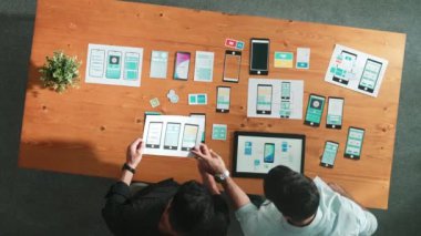 Yazılım geliştirici ekibi yazılım simgesi tutuyor ve cep telefonu arayüzü için Ux Ui tasarımı hakkında tartışıyorlar. Programcının üst görüşü, prototip tasarımının beyin fırtınası için birlikte çalışıyor. Cemaat.