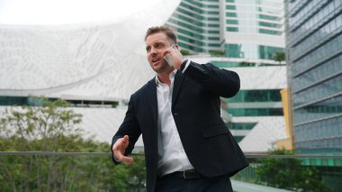 Zeki beyaz iş adamı, çatıda dururken iş arkadaşını mali strateji planlaması için arıyor. Proje yöneticisi pazarlama ekibiyle iletişim kurmak için cep telefonunu kullanıyor. Yaşam tarzı. Urbane.