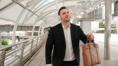 Şehir merkezinde Briç oynarken kulaklık takan mutlu bir iş adamı. Enerji yöneticisi neşeli ve motive edici performans yürürken başarılı projeyi kutlamak için müziğe geçiyor. Urbane.