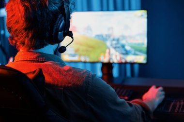 Genç oyun flamasının sunucu kanalı, takım oyuncusu, dijital neon odasında mikrofonlu kulaklık takarak bilgisayar ekranında çoklu oyuncuyla savaş oyunu oynuyor. Toplayıcı.