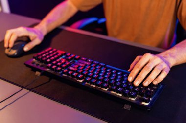 Bilgisayardaki klavye ve neon mavi ve pembe ışıklandırma siberinin faresiyle oynanan oyun odaklı ellerin yaratıcı görüntüsü. Takım yeteneğine sahip çok oyunculu oyun flaması kavramı. Bireysel.