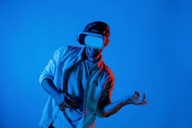 Beyaz adam hareket ediyor, gitar çalıyor ve arka planda ışık yansıması olan bir VR cam takıyor. Oyuncu metaevren ya da sanal gerçeklik programına teknolojik yenilikler kullanarak girer. Sapma.