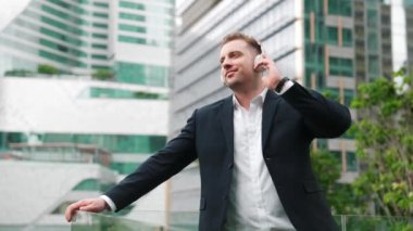 Çatıda müzik dinlerken kulaklık takan profesyonel bir işadamı. Kafkas proje yöneticisi gökdelene bakarken rahatlatıcı müziğe yöneliyor ve yeşil şehirde duruyor. Yaşam tarzı. Urbane.