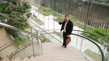 Kafkas işadamı akıllı telefon kullanarak müdürü arıyor ve mali raporları tartışıyor. Erkek lider, modern binada merdivenlerde dururken telefonla pazarlama ekibini konuşuyor. Urbane.