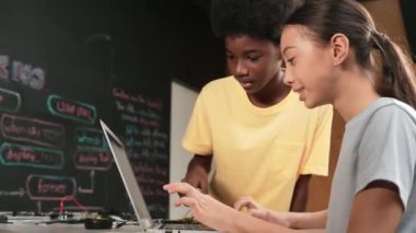 Tatlı kız dizüstü bilgisayar kodlaması yazarken ya da mühendislik sistemini programlarken mutlu Afrikalı çocuk ekranı işaret ediyor. BTMM teknoloji sınıfında dizüstü bilgisayar tutarken öğretmen eğitim programı. Öğretim