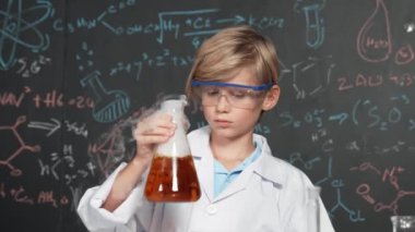 Akıllı çocuk, laboratuvar şişelerinde karışık kimyasal sıvıları dikkatlice inceler. Beyaz çocuk kimya dersi ya da BTMM fen dersinde bir deney yapmaya odaklan. Etkinlik.